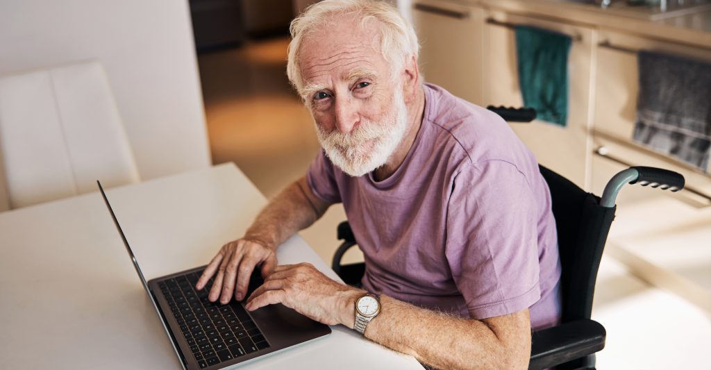 Pensioner in a wheelchair behind a PC