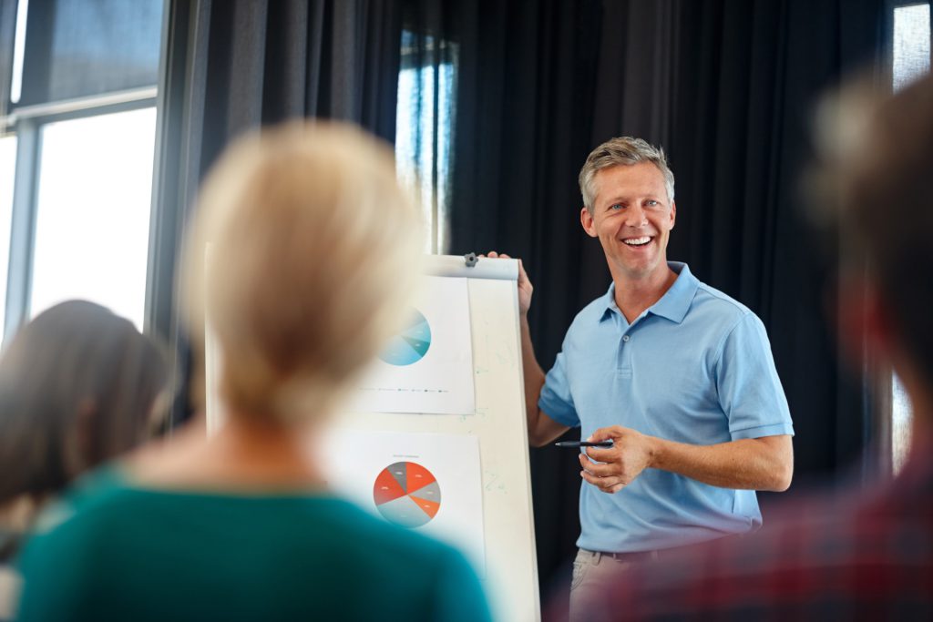 A smiling man holding a presentation