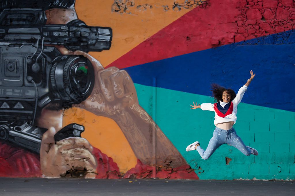 A happy woman dancing in front of a graffiti wall